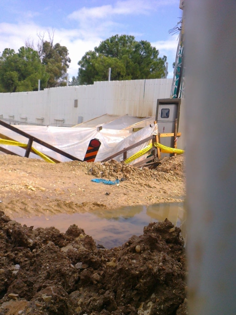  IAA excavation pit inside SWC construction site covered with plastic  tarp, supplied with dedicated electrical current for operating heavy  machinery and surrounded with warning tape