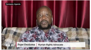 Image from Democracy Now interview with Pepe Onziema who is visible on the screen, sitting with a red background. On the screen is says Pepe Onziema human rights advocate. He is conducting the interview from Kampala, Uganda.