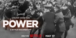 Cover image of the POWER documentary. Streaming on Netflix starting on Friday, May 17.  The image is a black and white photo of a large group of cops surrounding someone.