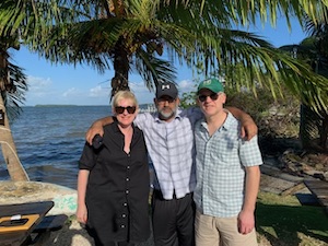 image of our client with his two lawyers in a tropical beach setting