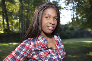 image of our client ashley diamond a Black trans woman who is currently incarcerated in the georgia department of corrections system. she is in a park surrounded by trees looking at the camera and smiling