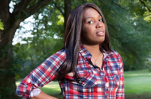 image of our client ashley diamond she is wearing a plaid long sleeve shirt and is in a park surrounded by trees
