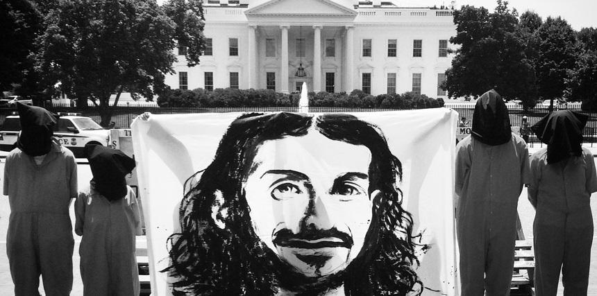 Protesters hold a banner image of Guantanamo prisoner Tariq Ba Odah outside the White House