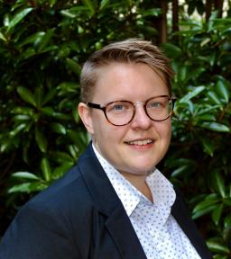 Headshot of CJ Sandley in jacket and white shirt