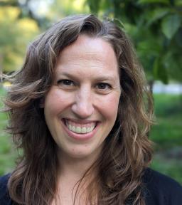 Headshot, smiling, in front of greenery