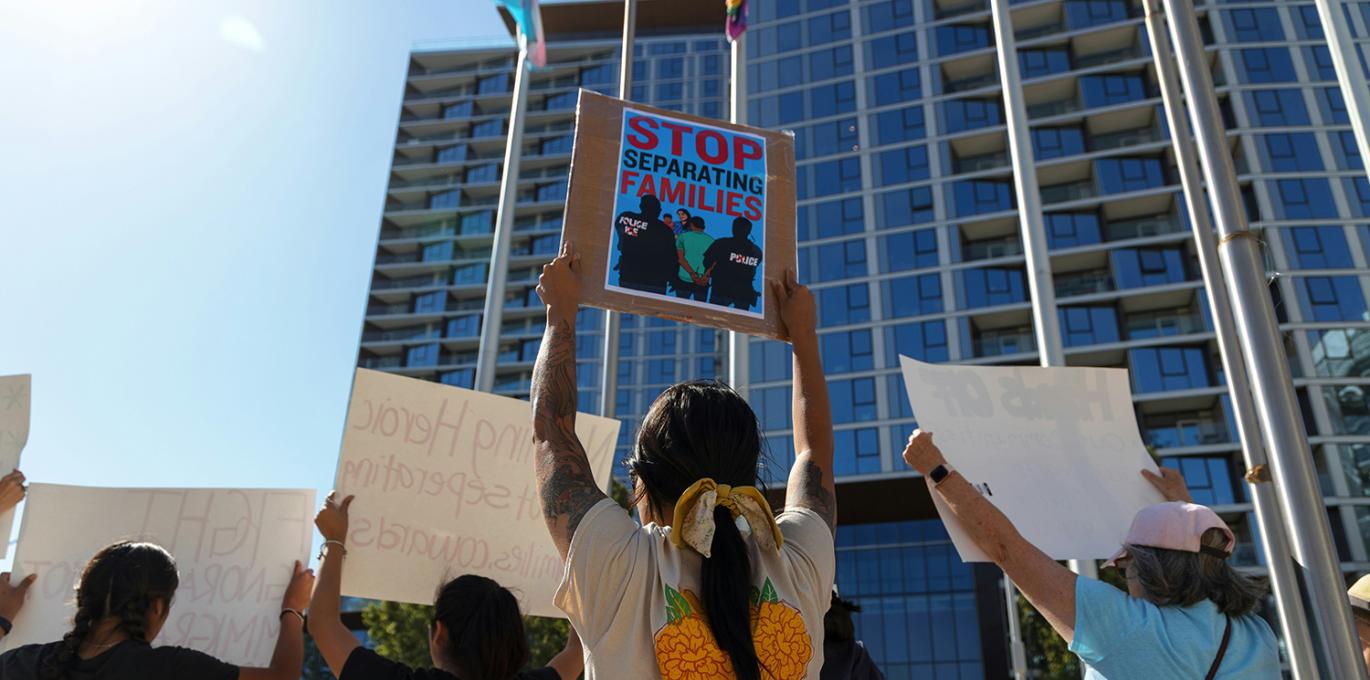 Protesters marching with one holding up sign, "Stop separating families"