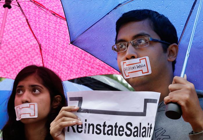 Students with their mouths taped shut holding a sign that reads "Reinstate Salaita"