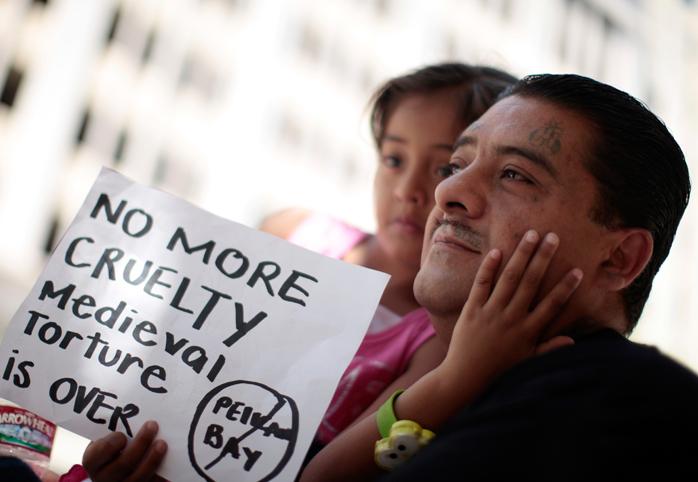 A father and daughter at a protest holding a sign that reads "NO MORE CRUELTY"